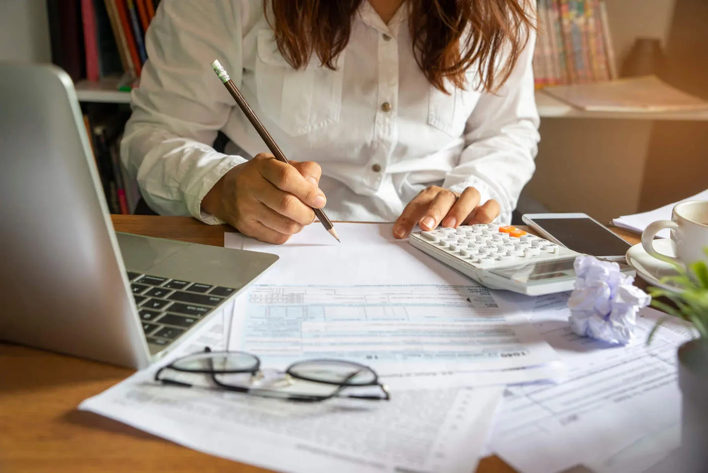 Woman calculating workers' compensation benefits taxes on paper.