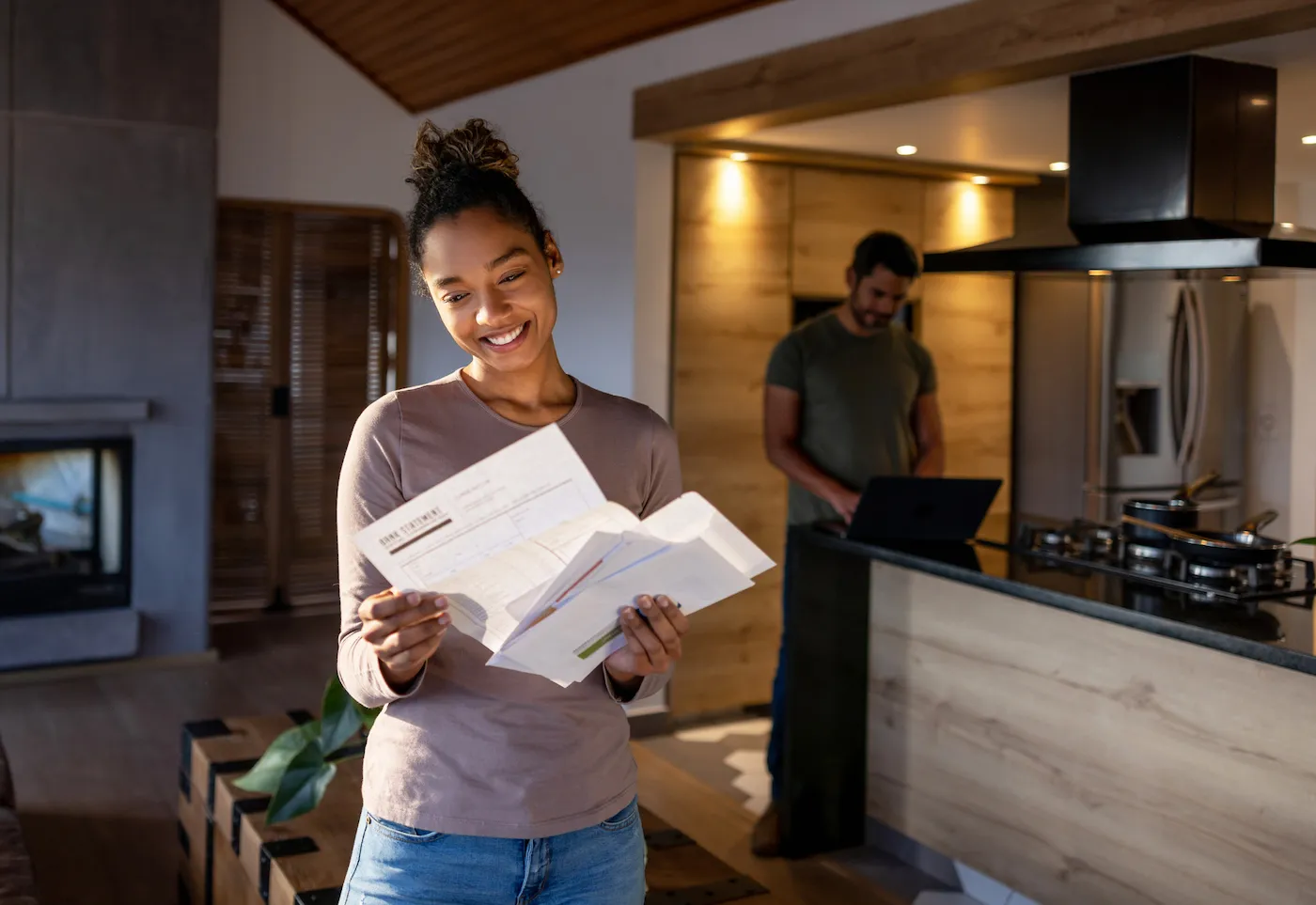 woman at home looking at a utility bill that came in the mail and smiling