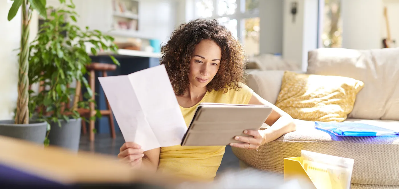 Woman comparing information on a piece of paper and a tablet