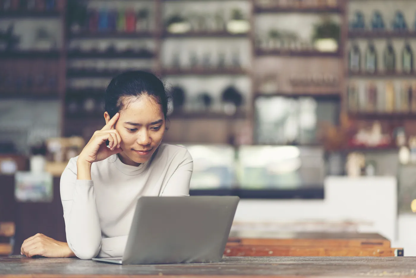 A woman is looking at her laptop, considering a personal loan to pay off her credit card.