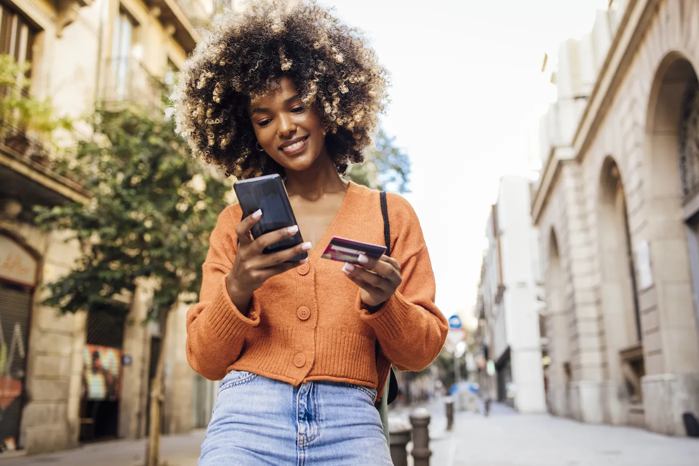 Happy woman in Barcelona shopping online on her phone using buy now pay later