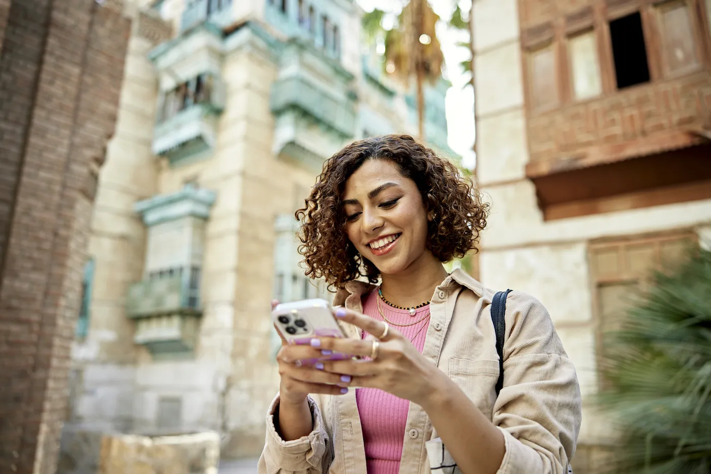 A smiling woman using her mobile phone to set up automatic payments.