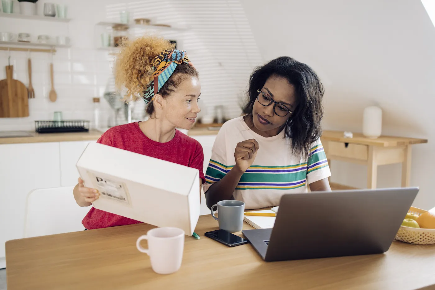 A woman receives a package that she ordered through social media, displaying it to her friend who looks skeptical.