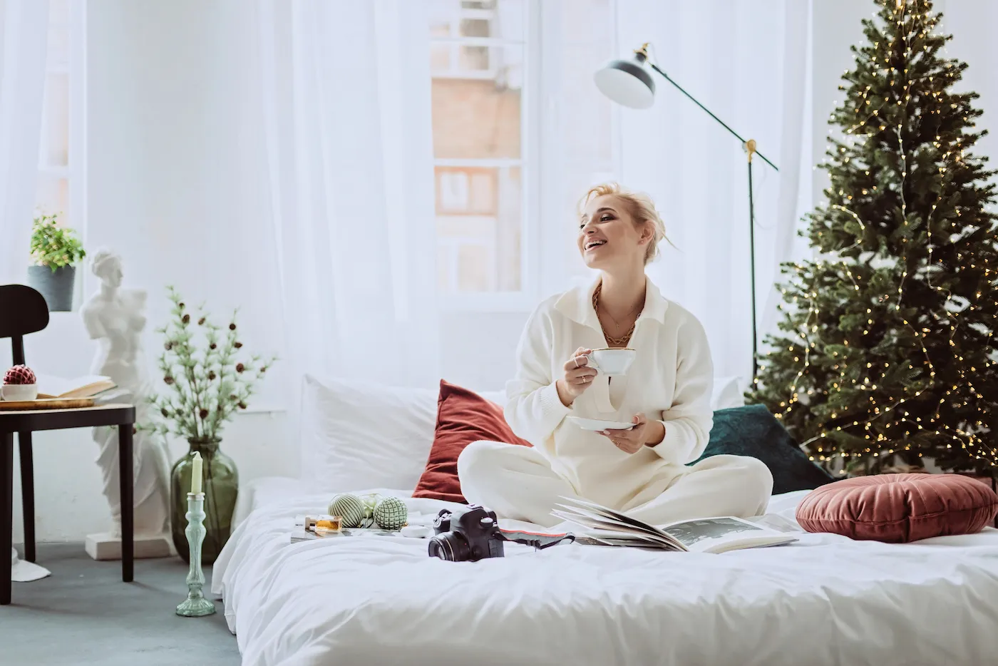 Woman sitting in bed on New Years with coffee and a tree