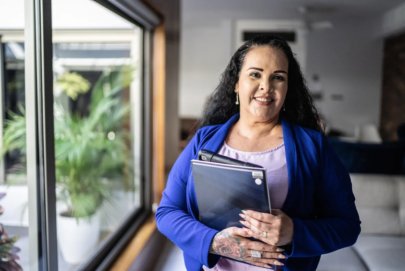 Woman standing in a house holding binders