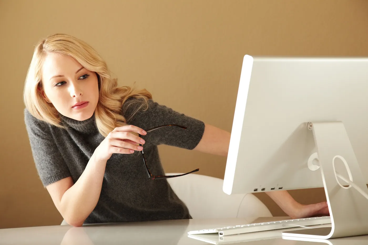 Woman looking around computer monitor, suspicious that she may be a victim of identity theft.