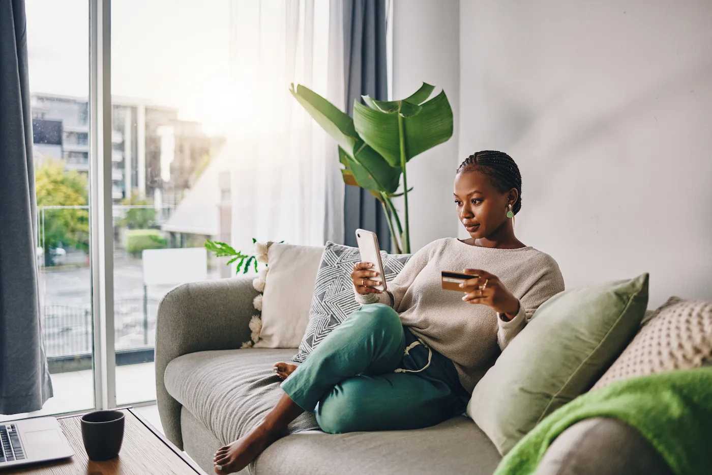 Woman using her credit card on her couch at home.