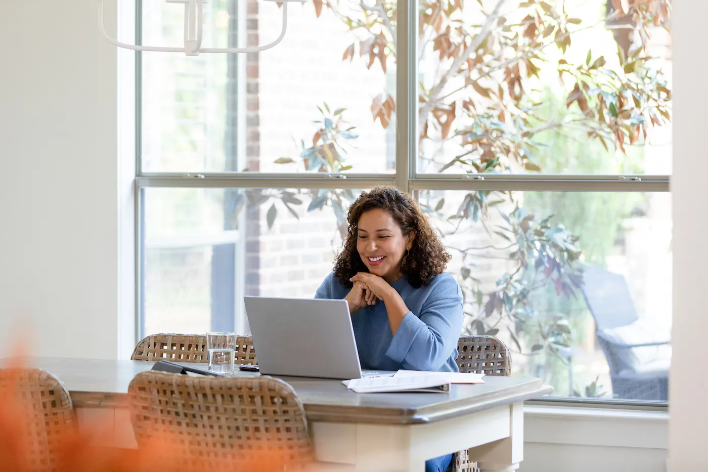 A woman sits in the dining room and uses her laptop for the flex modification program.