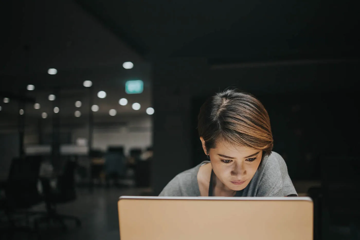 Woman working on laptop late at night.