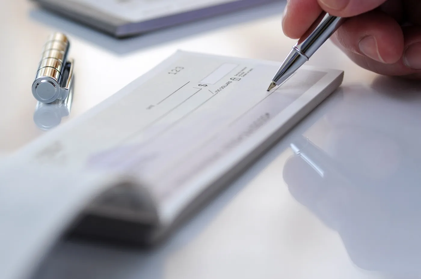 A hand holding a pen prepares to write a check in the office