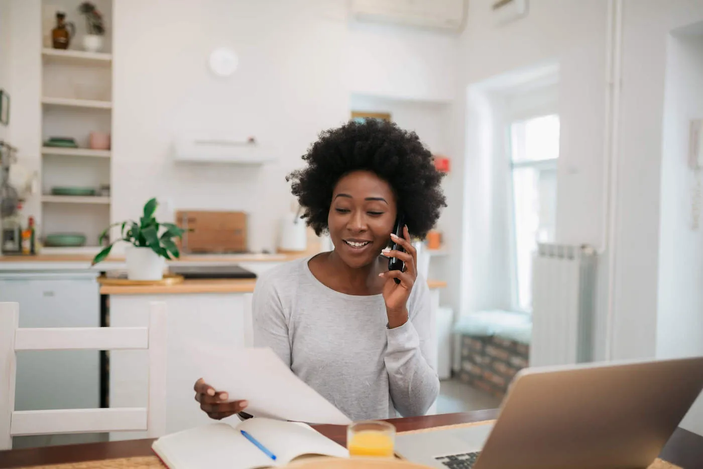 Young African American woman on the phone holding a piece of paper.