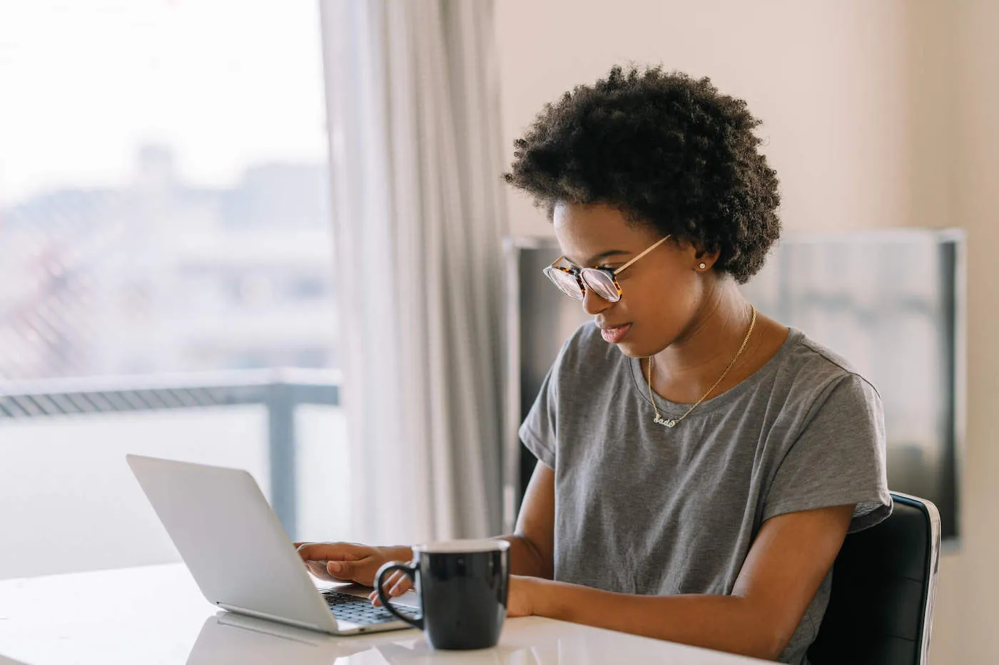 Young black woman using a laptop in the living room at home.