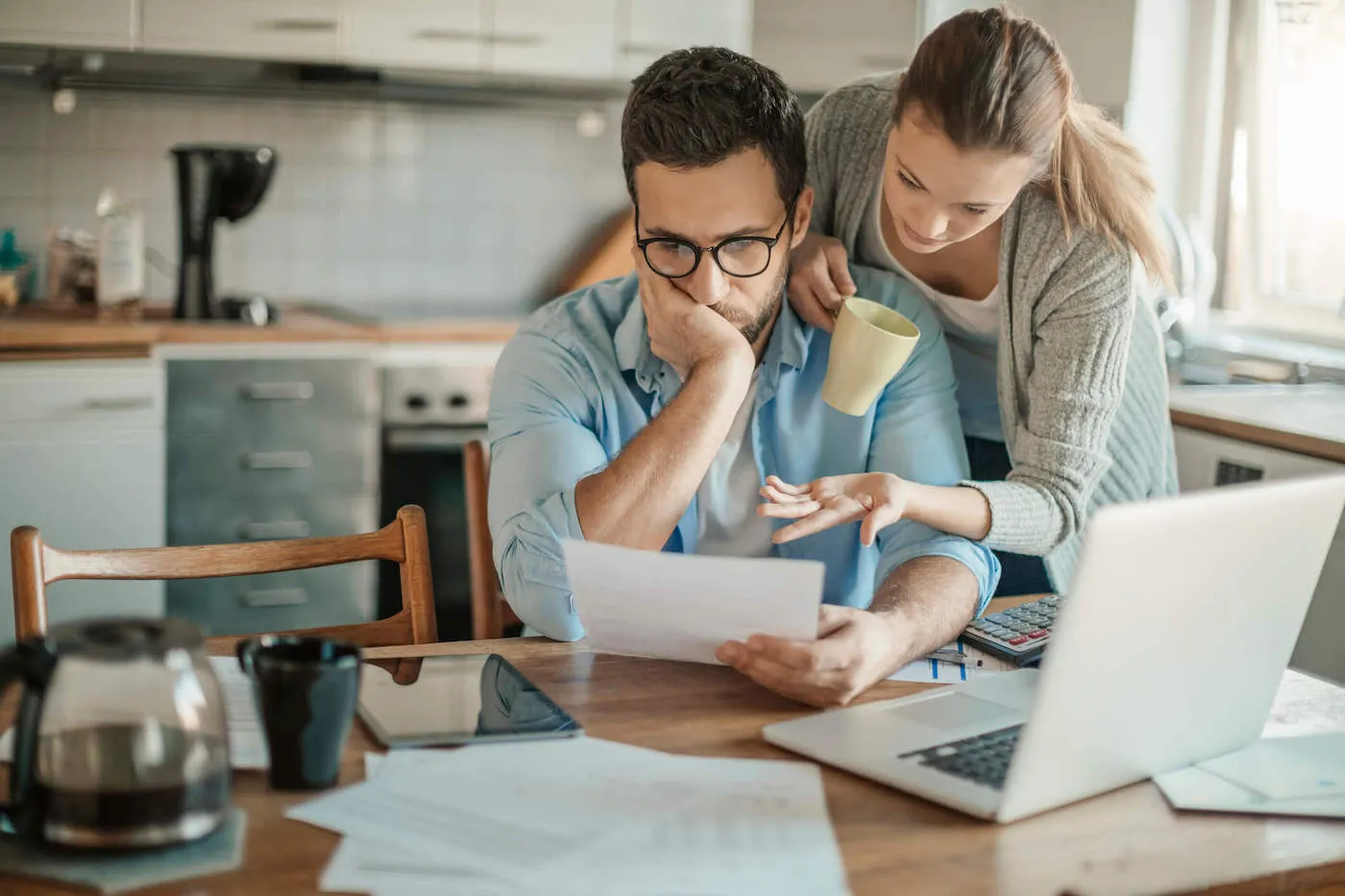 Young man and woman couple looking at piece of paper discussing bankruptcy.