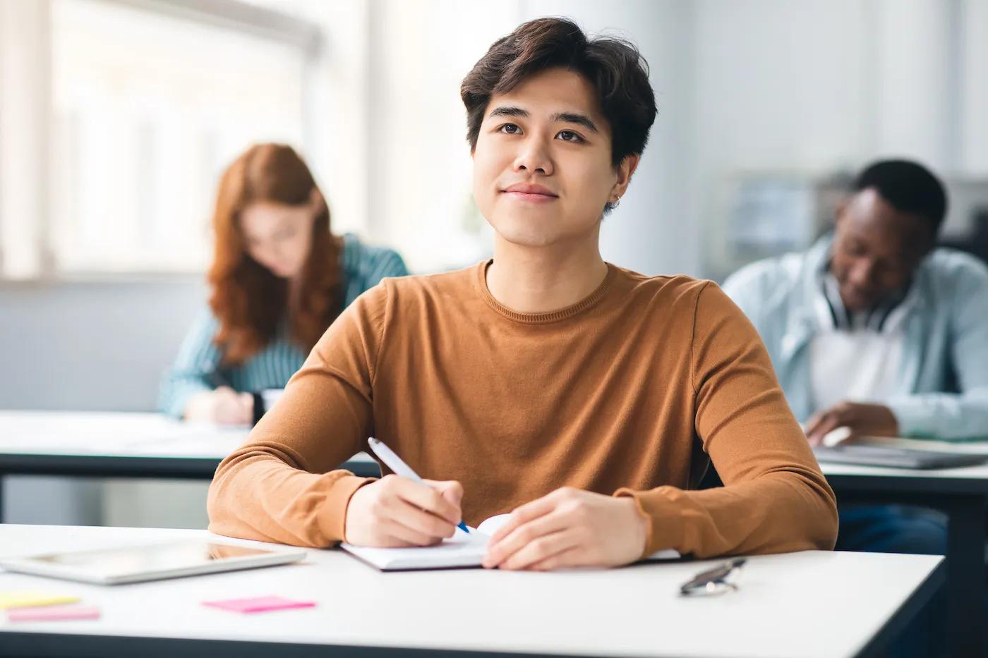 young man paying attention in class taking notes