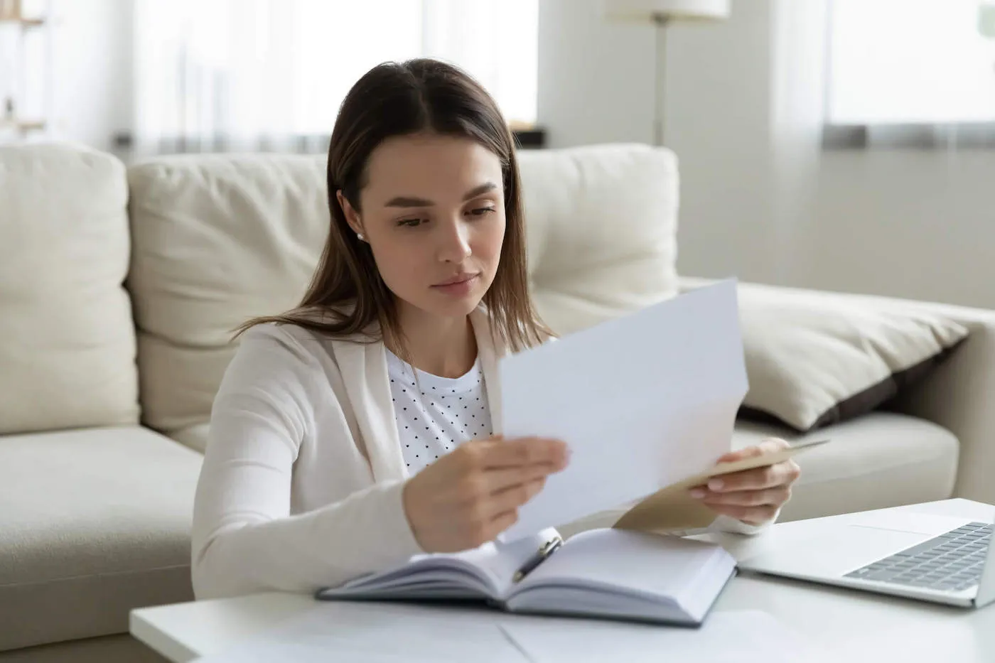 Young woman looking at a piece of paper while seated on the floor.