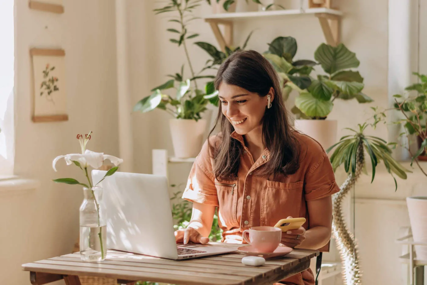 Young woman seated on a small desk researching online on her laptop.