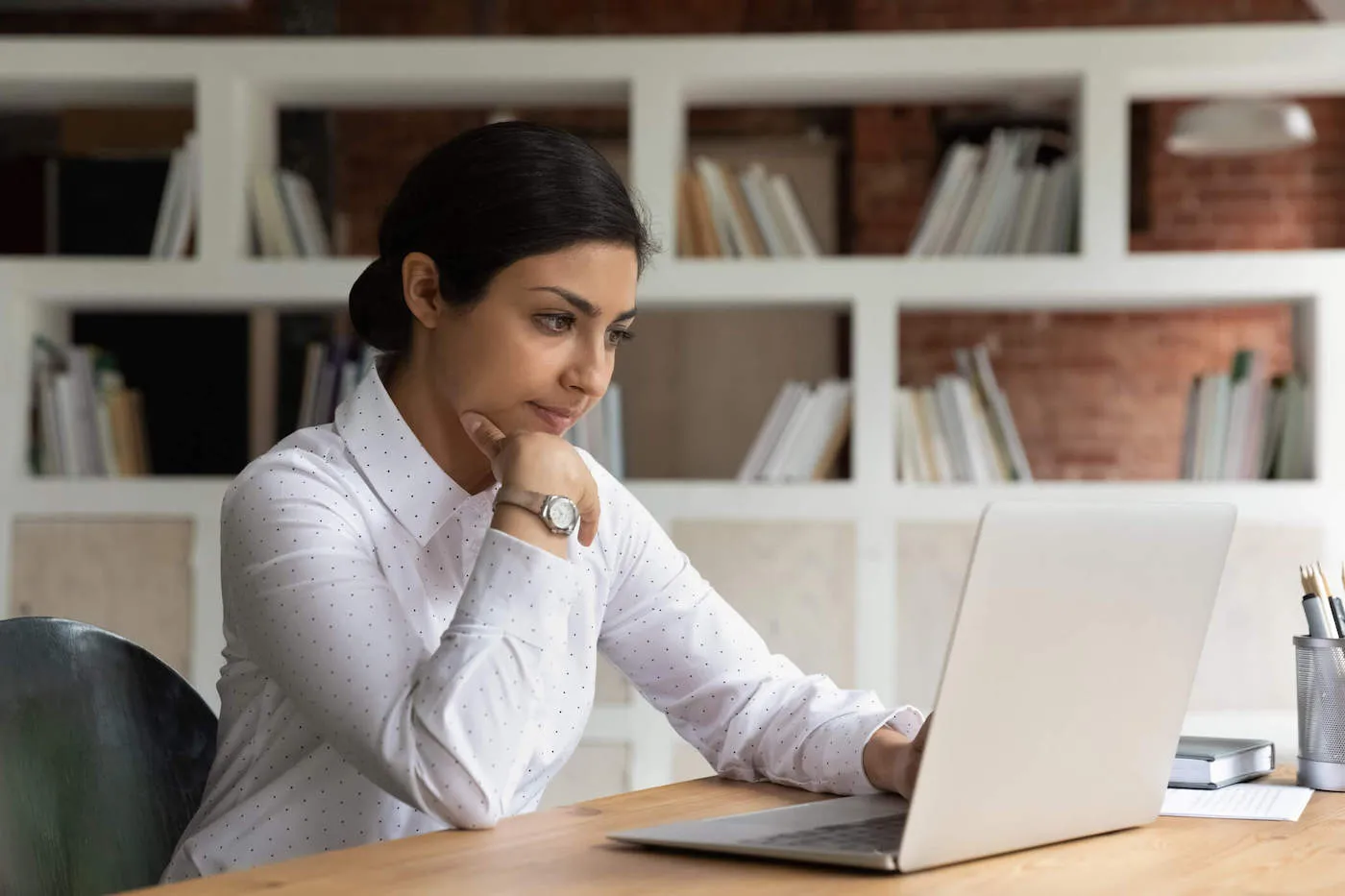 Young woman typing on laptop while researching.