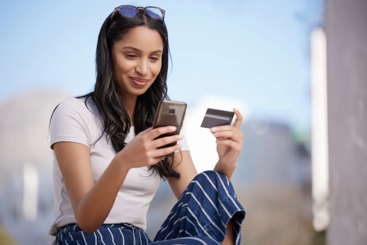 Young smiling woman holding credit card and phone