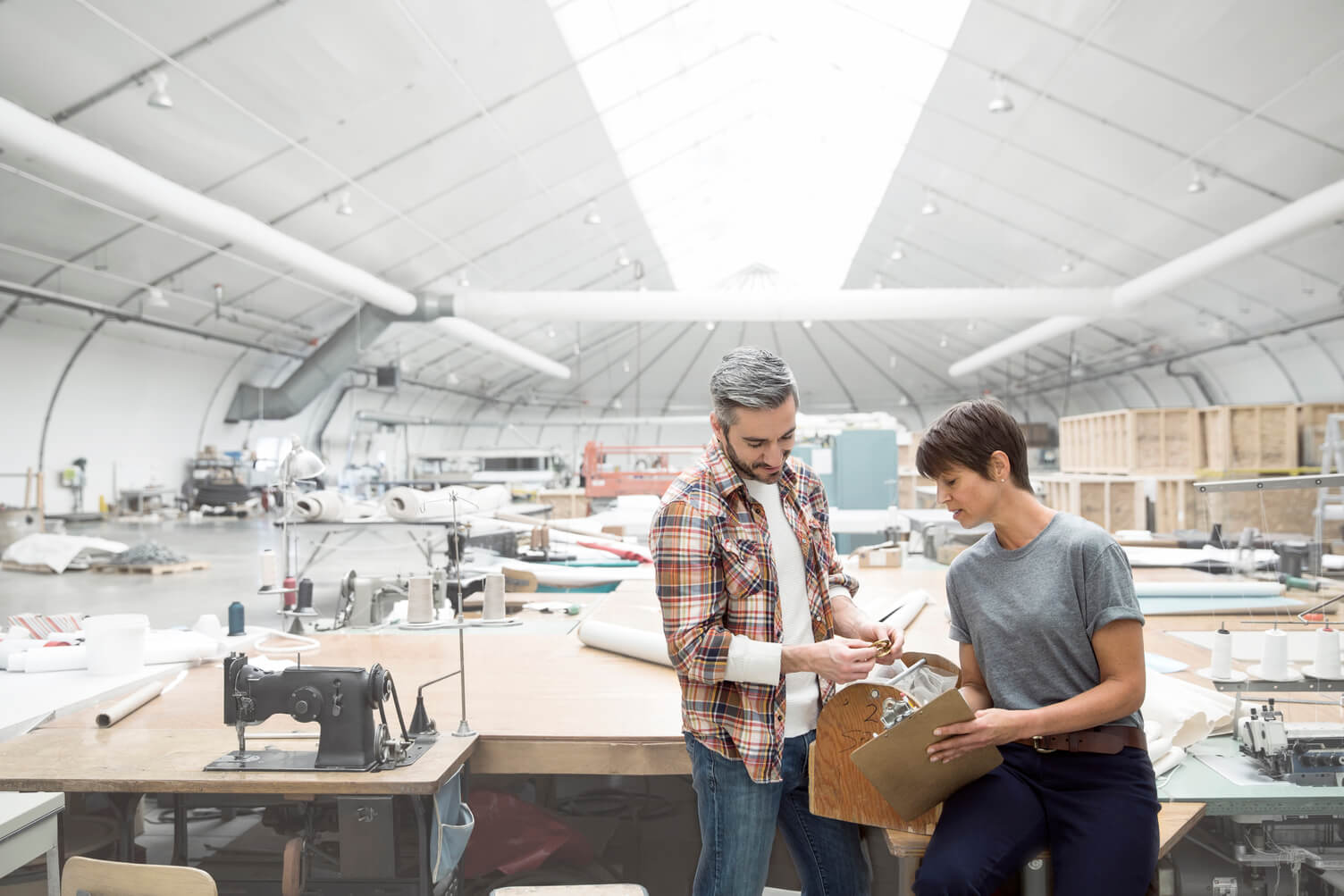 Man and woman discussing an object in a warehouse