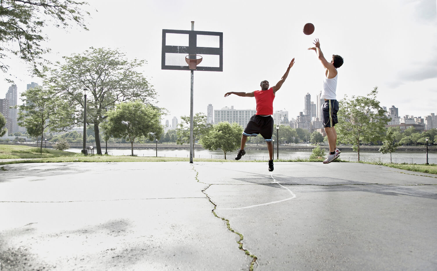 Two men playing basketball outside