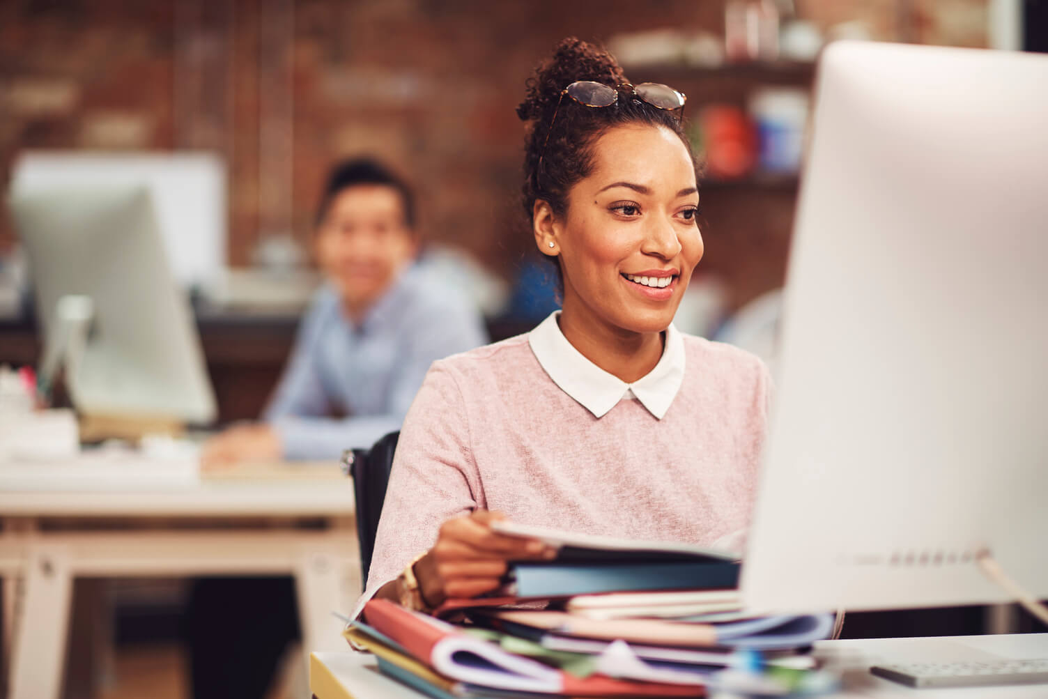 Example image of depth of field with camera focused on woman working on computer with male colleague in background out of focus