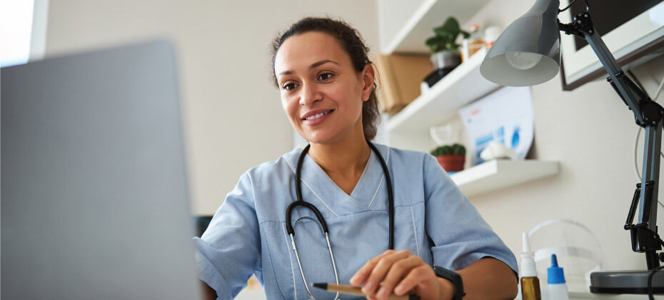 nurse smiling at a desktop computer